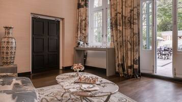 A room with a large window, a door, a table with a vase, and a sofa.