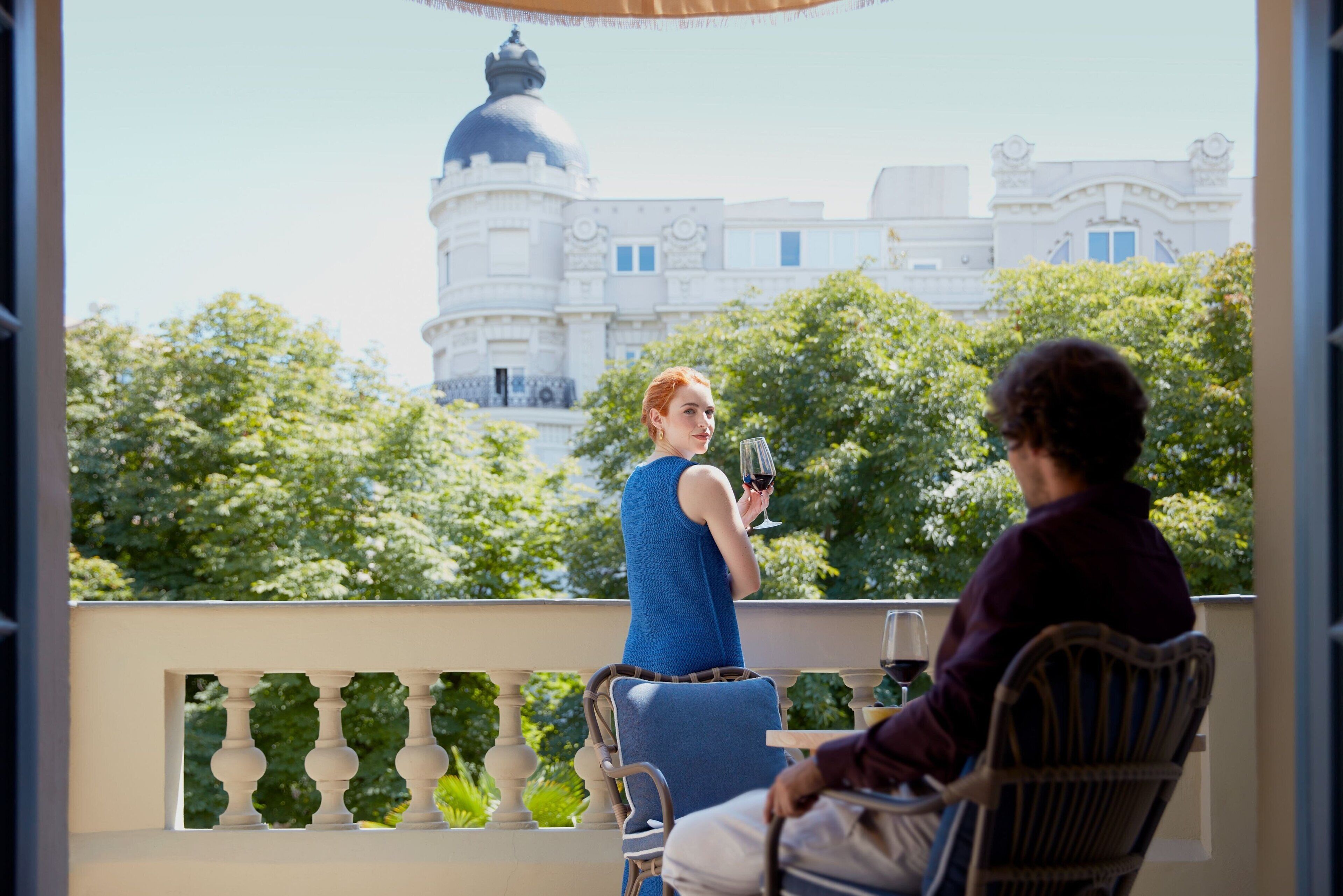 A balcony with a view of a building with a dome and trees in the background.