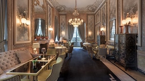 Um hall de hotel luxuoso, com decoração requintada, um lustre imponente e vista para o exterior.