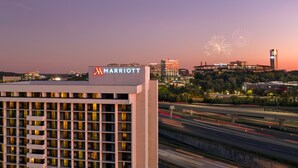A Marriott hotel with a modern facade, a view of the city skyline, and fireworks in the background. - Atlanta Marriott Northwest at Galleria (Atlanta)