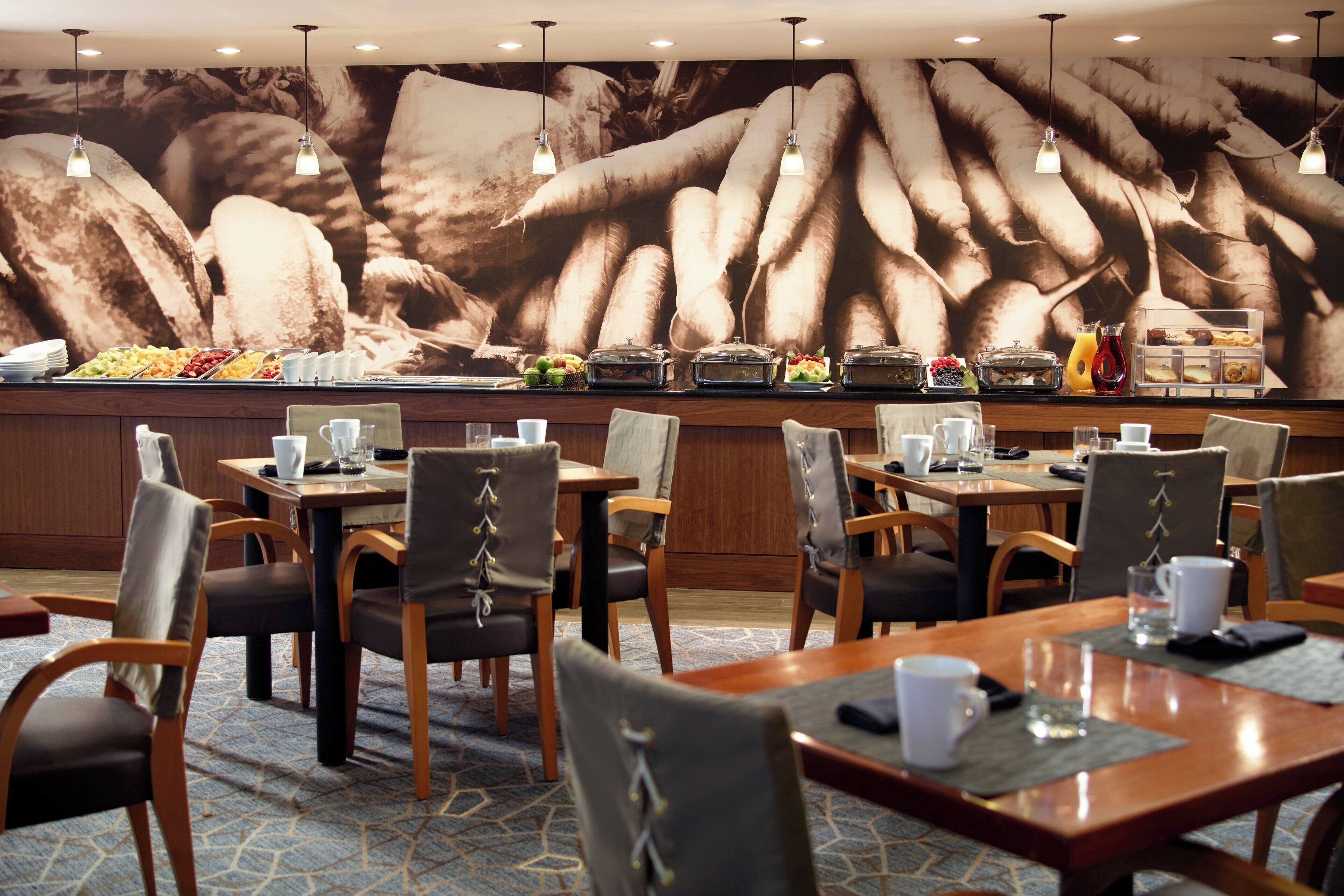 A breakfast buffet area with various food options and a seating area with tables and chairs.