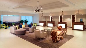 A modern lobby with a curved sofa, a wooden sculpture, and a reception desk.