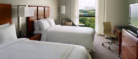 A hotel room with two beds, a TV, a desk, and a chair.