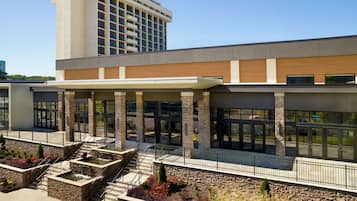 A modern hotel with a covered entrance, outdoor seating area, and a landscaped garden.