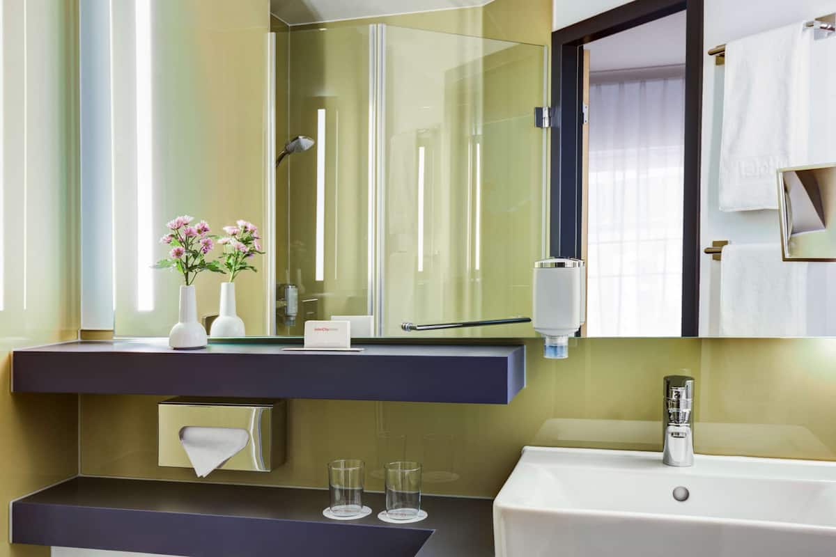 Un bany modern amb una cabina de dutxa de vidre, un lavabo blanc i un mirall sobre la superfície.
