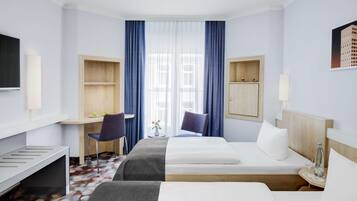 A hotel room with two beds, a desk, a chair, a TV, and a window with curtains.