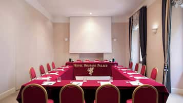 Un salón de conferencias con una larga mesa, sillas rojas y un cartel que dice 'Hotel Brufani Palace'.