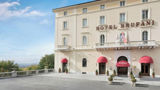 Ein Hotel mit auffälligem Namen, mehreren Fenstern und einem Balkon mit Flaggen.