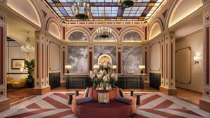 A lobby with a round seating area, a large window with a view, and a chandelier. - Sina Brufani (Perugia)