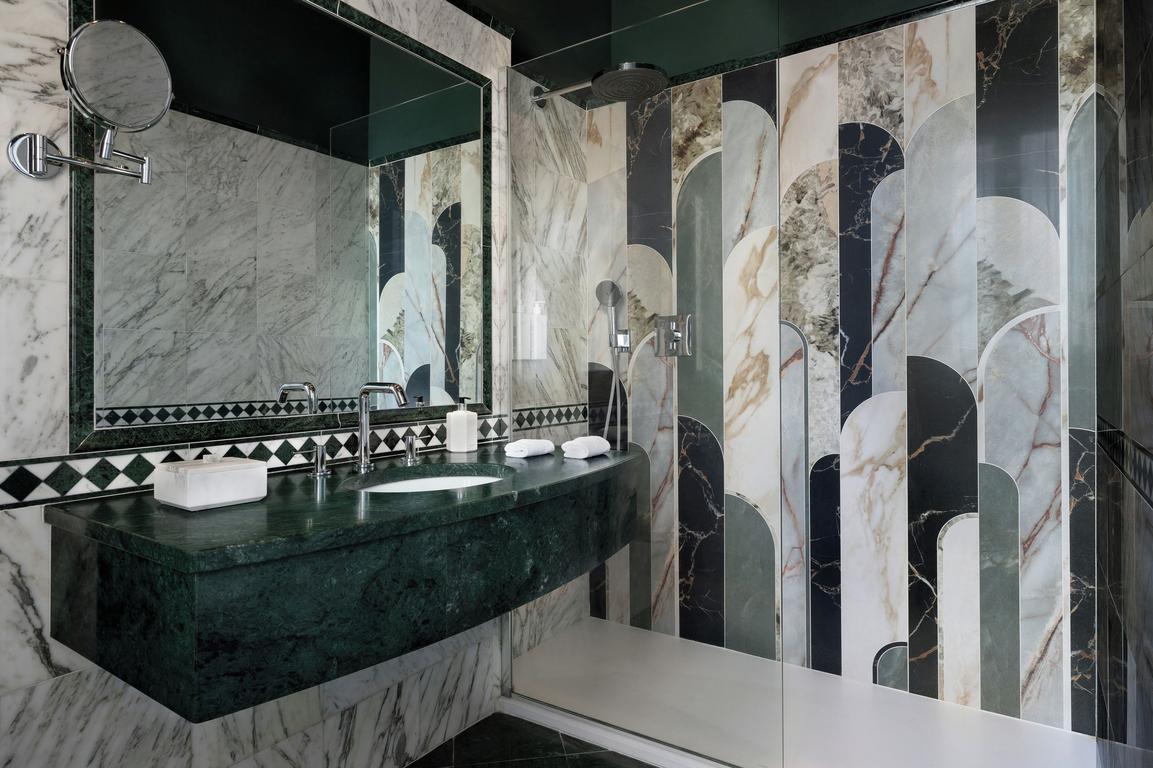 A bathroom with a marble sink, a large mirror, and a shower area.