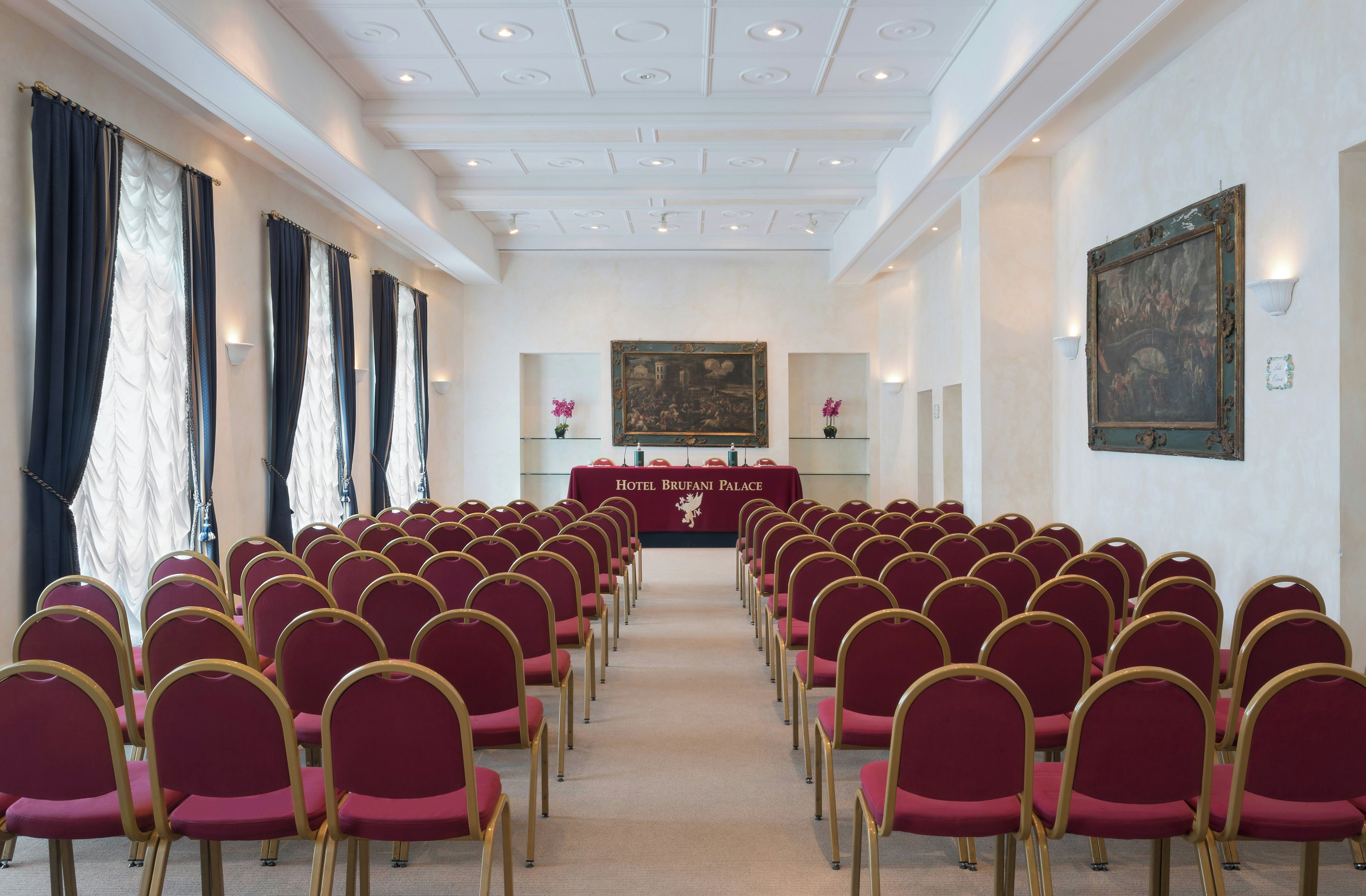 A conference room with rows of chairs, a table with a banner, and artwork on the walls.
