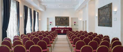 A conference room with rows of chairs, a table with a banner, and artwork on the walls.