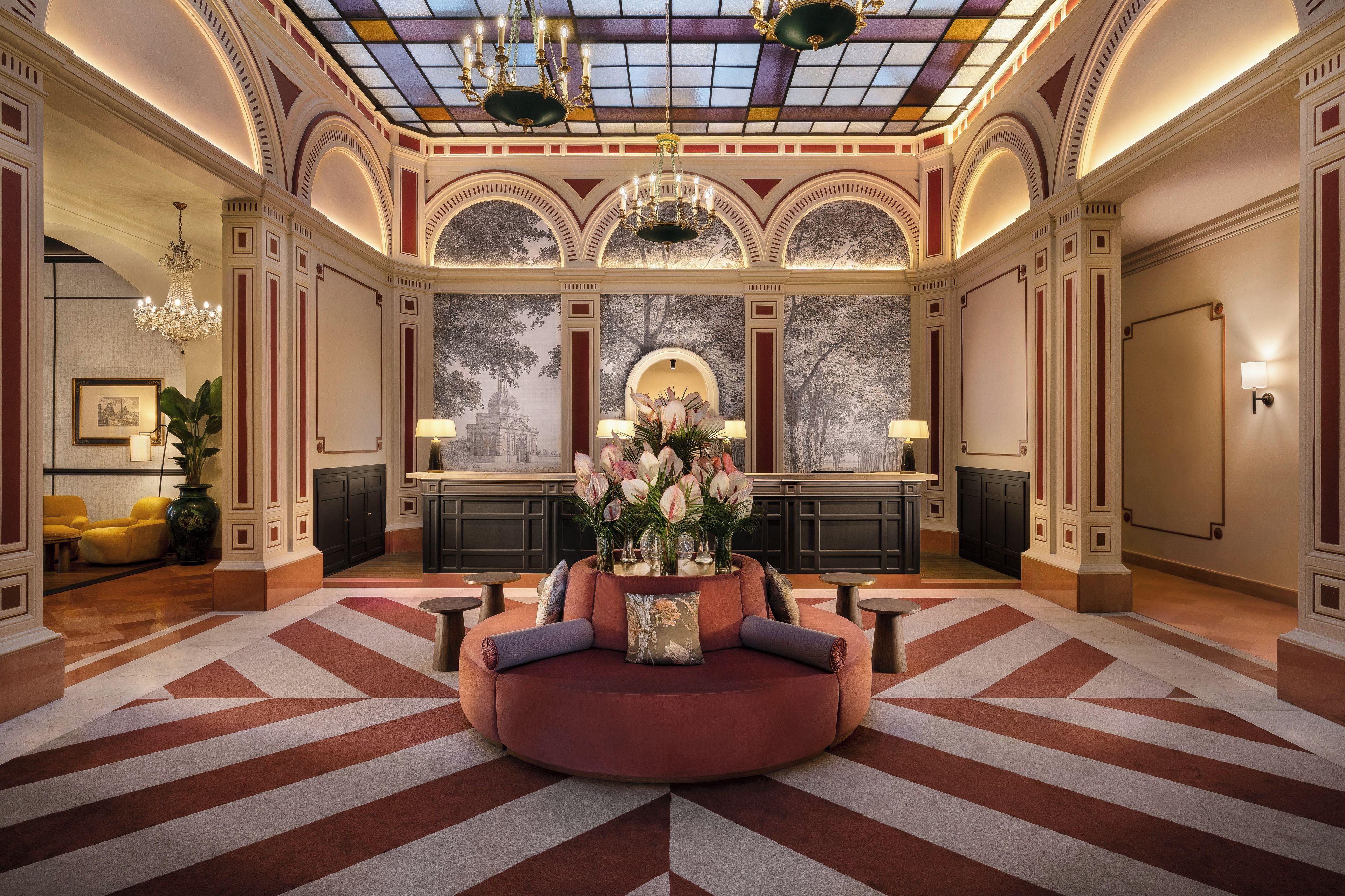 A lobby with a round seating area, a large window with a view, and a chandelier.