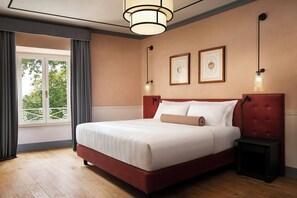 A neatly made bed with a red headboard, a bedside table, and a window with curtains. - Sina Brufani (Perugia)