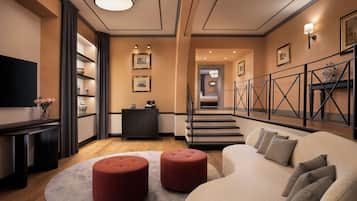 Un salon moderne comprenant un canapé, des poufs, un téléviseur à écran plat, une cheminée et un escalier menant à un autre niveau.