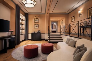 A modern living room with a sofa, ottomans, a flat-screen TV, a fireplace, and a staircase leading to another level. - Sina Brufani (Perugia)