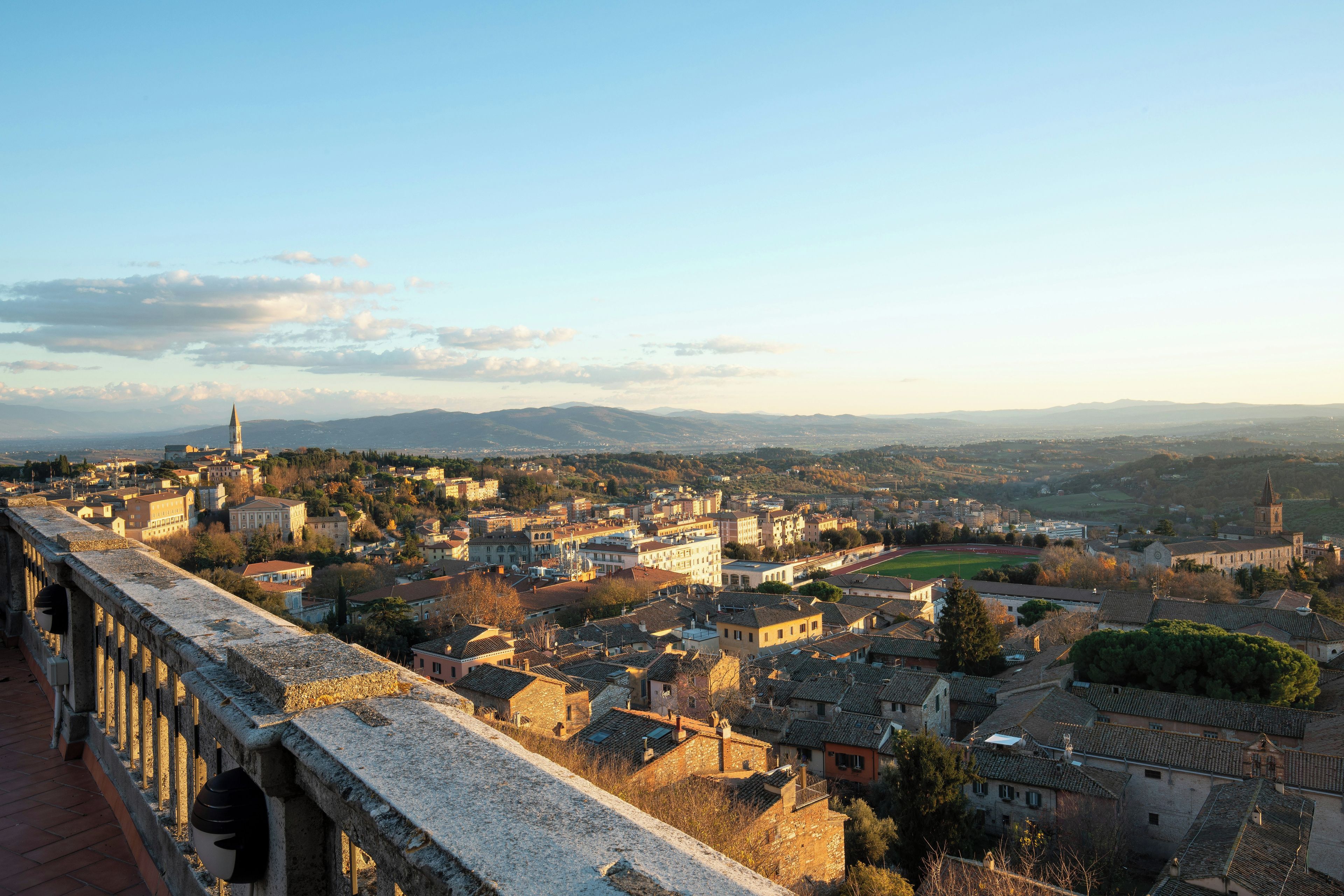 Un pueblo histórico con una imponente torre de iglesia, un puente de piedra y vistas al campo circundante.