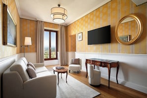 Una sala de estar con sofá, sillones, una mesa de centro, televisión y escritorio.