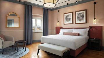 Ein Schlafzimmer mit einem großen Bett, einem Sessel, einem kleinen Tisch und zwei gerahmten Bildern an der Wand.