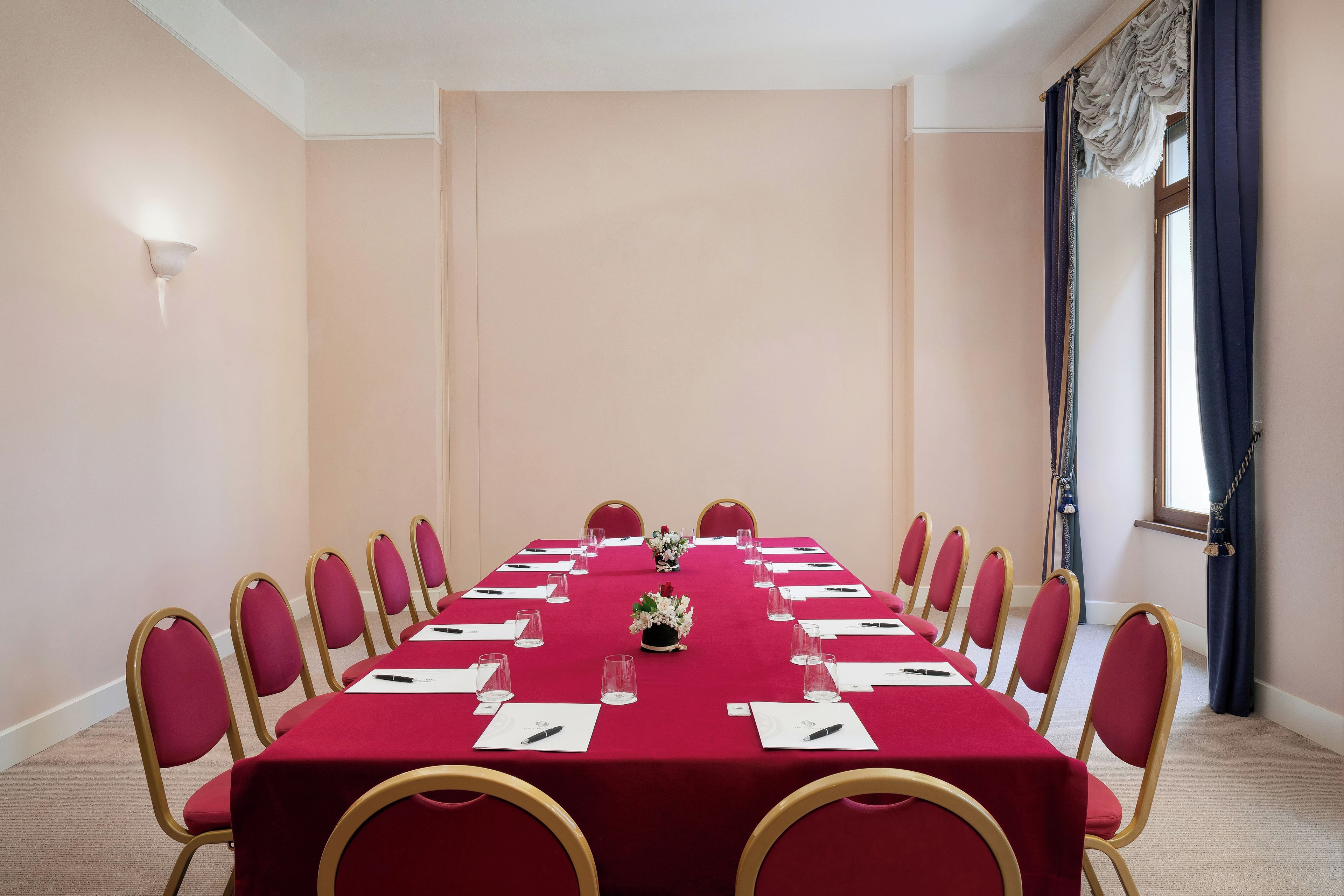 Ein Konferenzraum mit langem Tisch, Stühlen und einer floralen Tischdekoration.