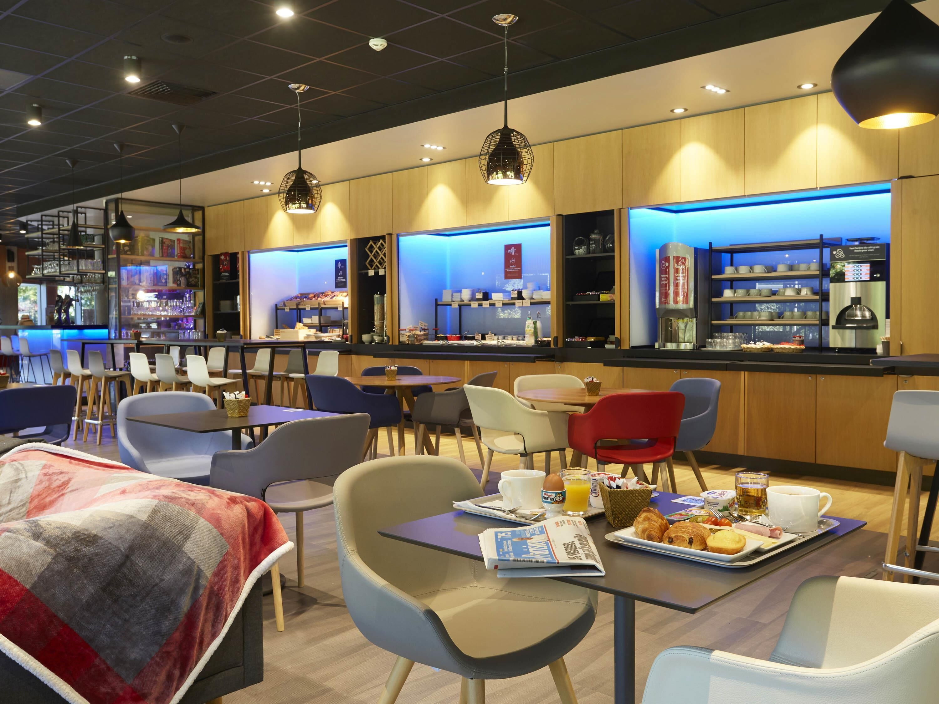 A modern cafe with seating, a bar area, and breakfast items on tables.