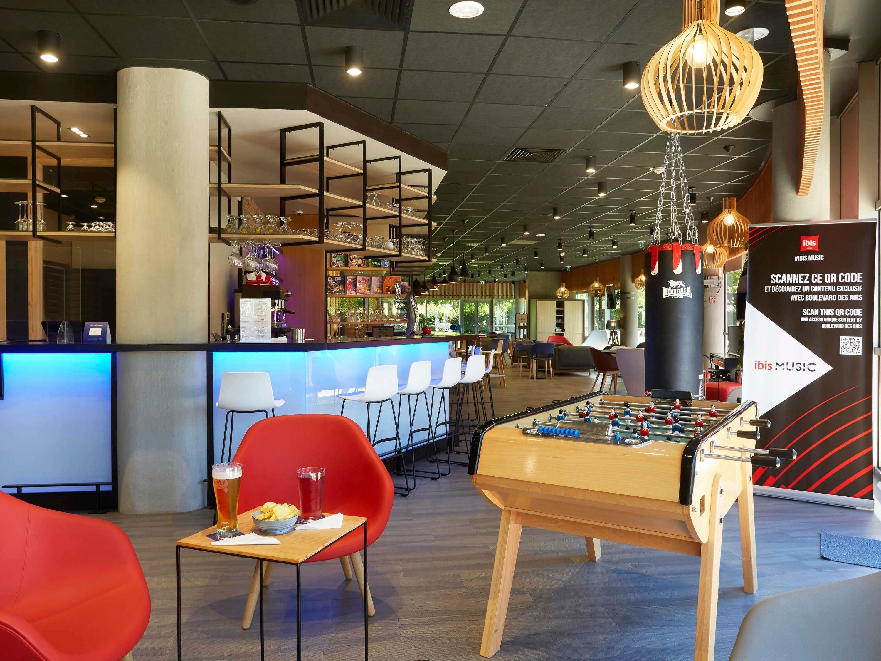 A modern bar area with a foosball table, seating, and a bar counter.