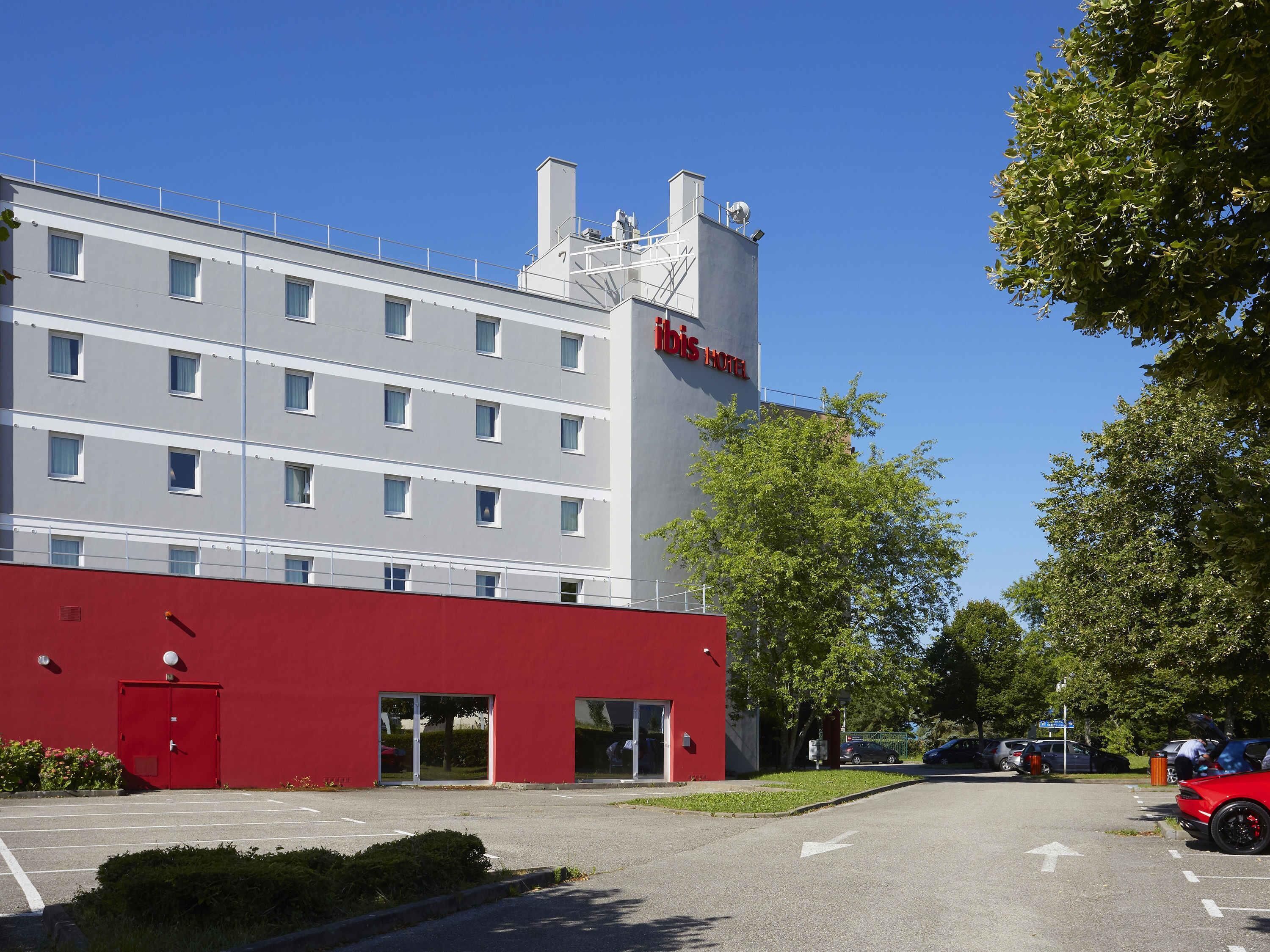 A hotel building with a red facade, multiple windows, and a clear sky.