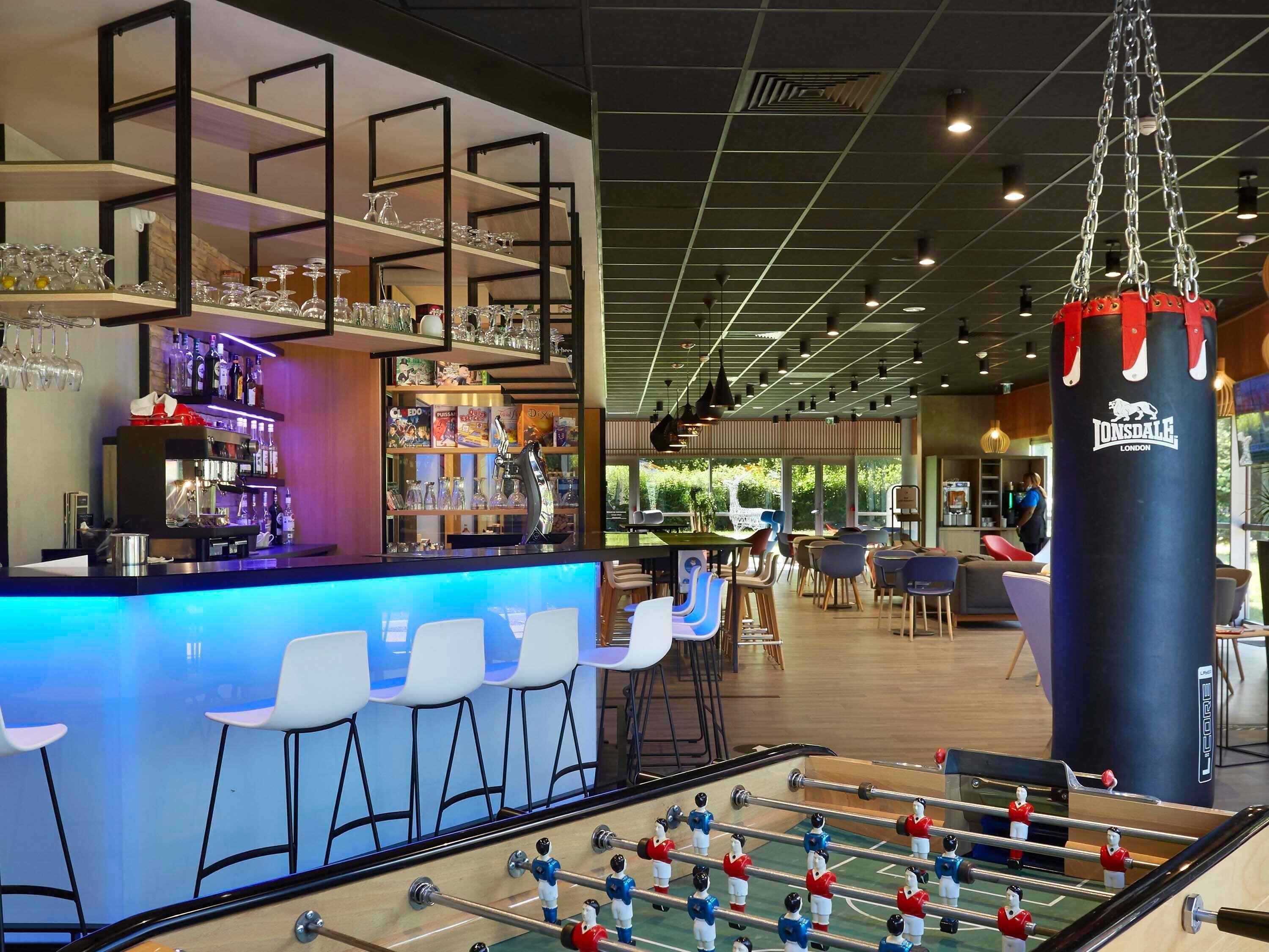 Una zona de bar con taburetes, una mesa de fútbol de mesa y un saco de boxeo.