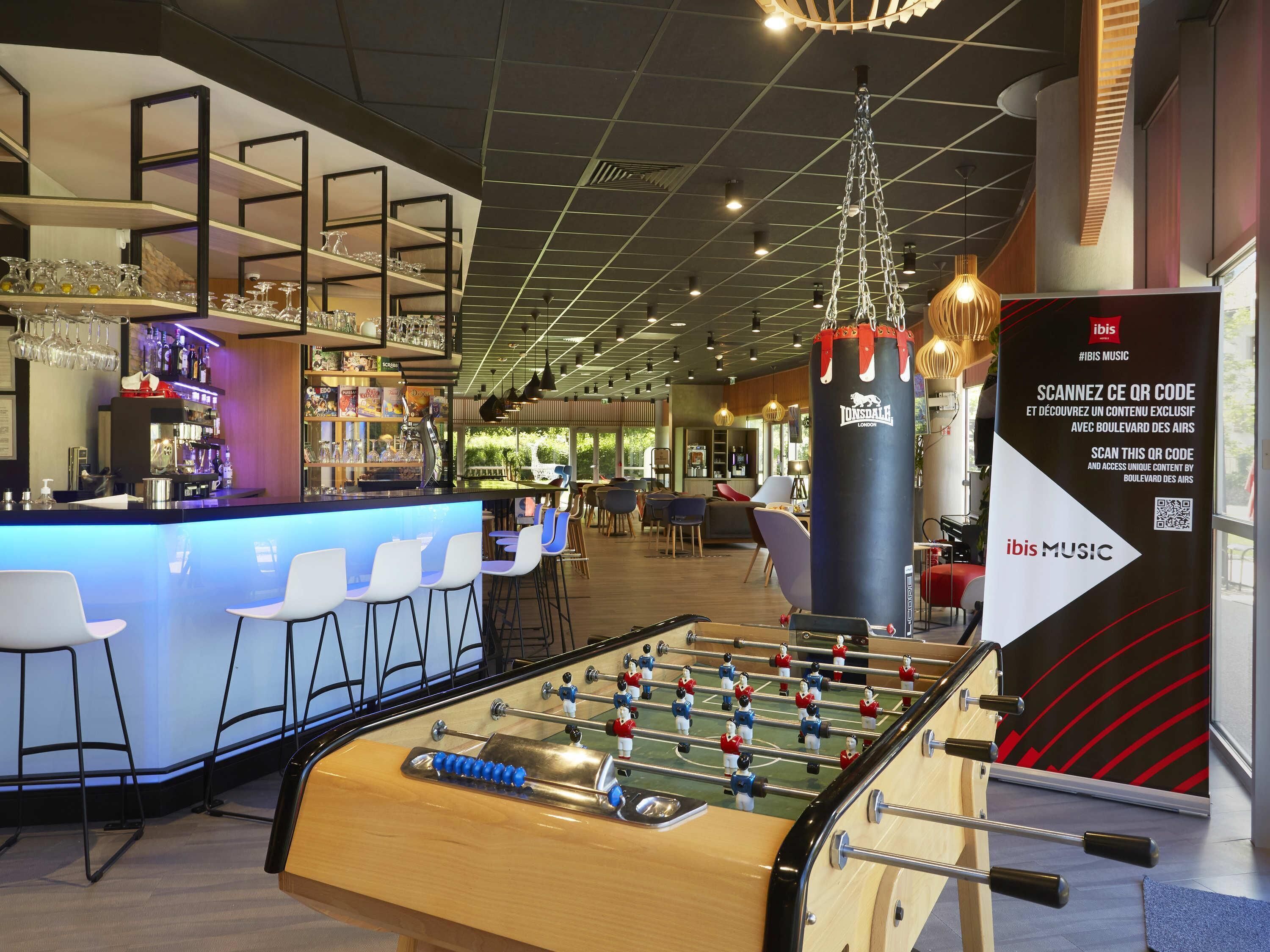 Zona de bar moderna con una mesa de fútbol de mesa, asientos y barra.