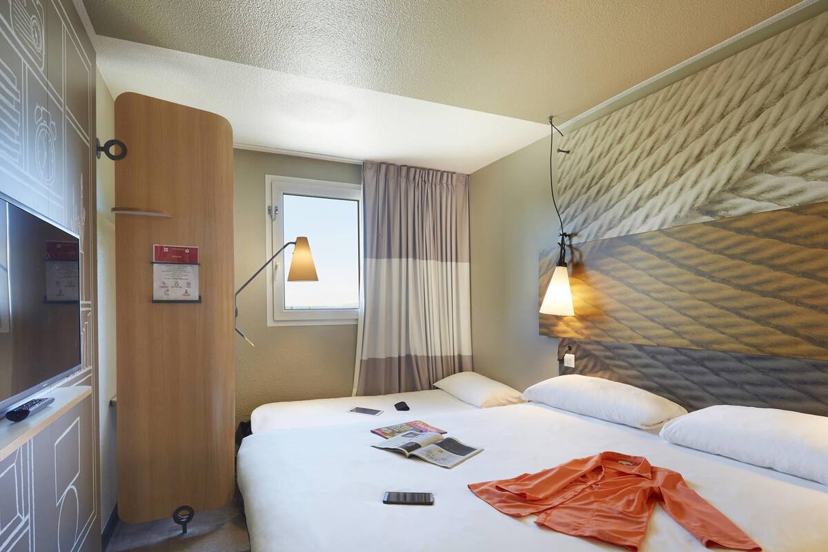 Een hotelkamer met een bed, een bureau, een lamp en een raam.