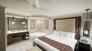 A hotel room with a large bed, a separate bathroom with a bathtub, a vanity with a mirror, and a ceiling fan. - Eden Resort and Suites, BW Premier Collection (Lancaster)
