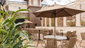 An outdoor patio area with wicker furniture, string lights, and a large umbrella. - Eden Resort and Suites, BW Premier Collection (Lancaster)