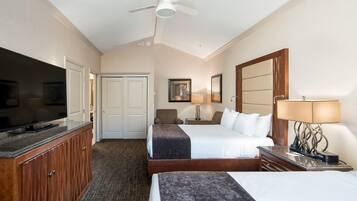 A hotel room with a bed, a desk, a television, and a ceiling fan.