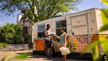 A food truck named 'Splashers' by Eden Resort, parked on a paved area with a stone wall and trees in the background.