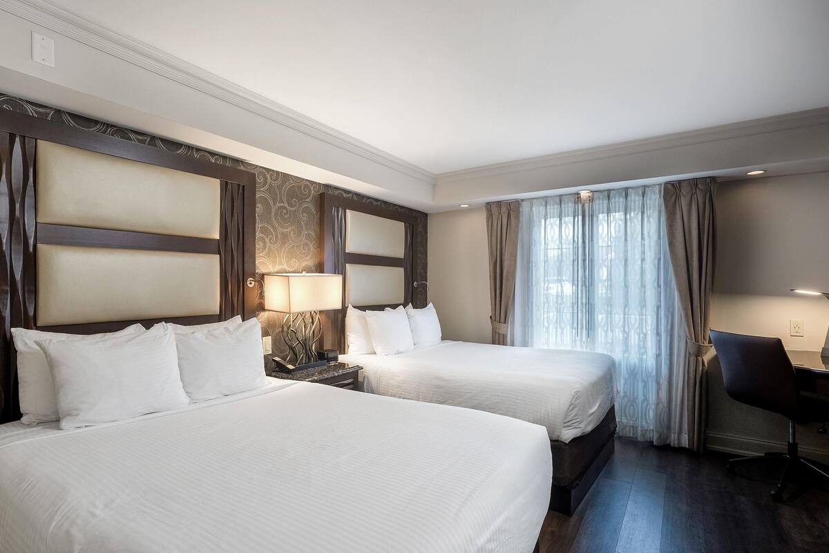 Habitación de hotel con dos camas, un escritorio y una silla.