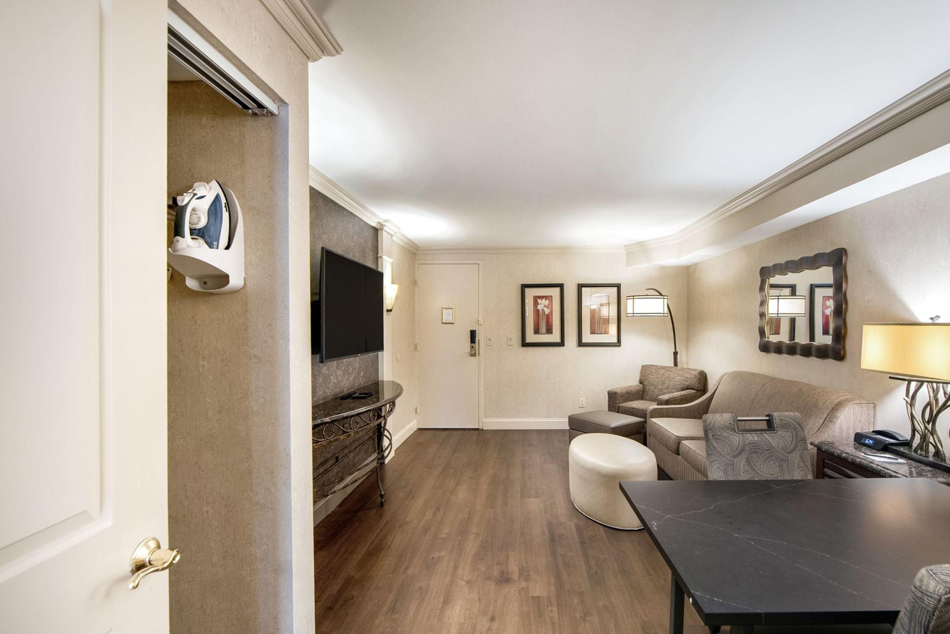 Habitación de hotel con comedor, sofá, televisor y espejo.
