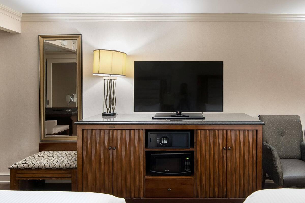 Una habitación de hotel con televisión, lámpara, microondas, una silla y una cama.
