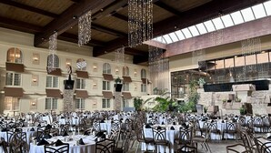 A spacious indoor dining area with multiple tables and chairs, large windows, and hanging lights. - Eden Resort and Suites, BW Premier Collection (Lancaster)