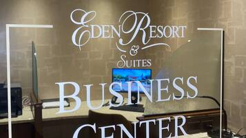 A business center at Eden Resort Suites with a computer, printer, and a television screen.