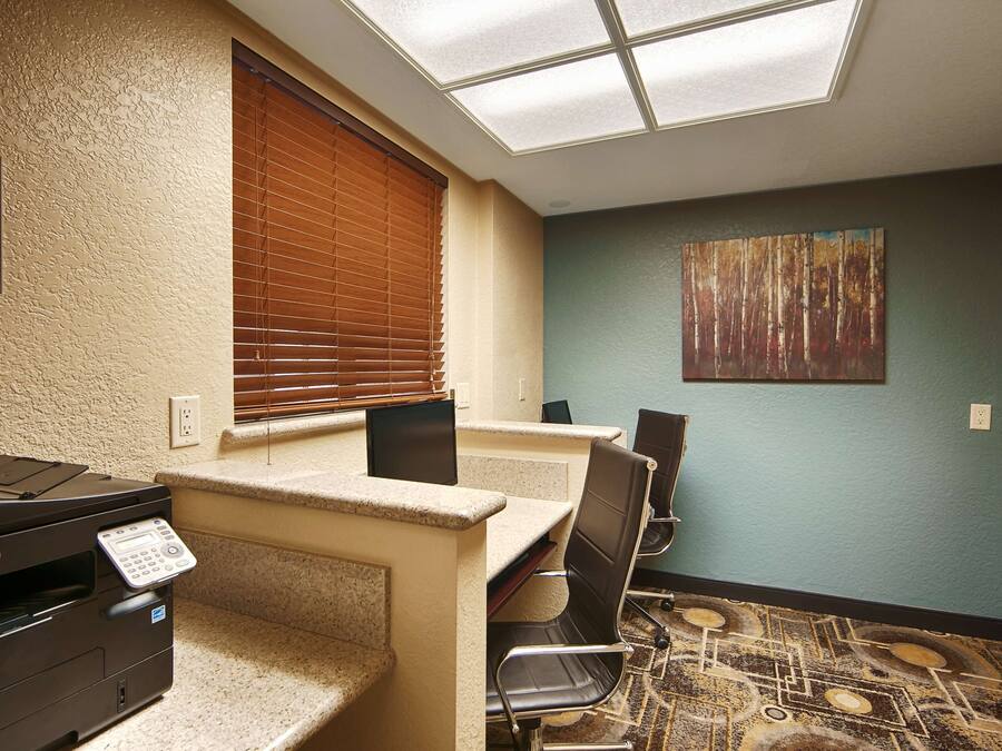 A business center with a Dell printer, a computer, and a seating area with chairs and a table.