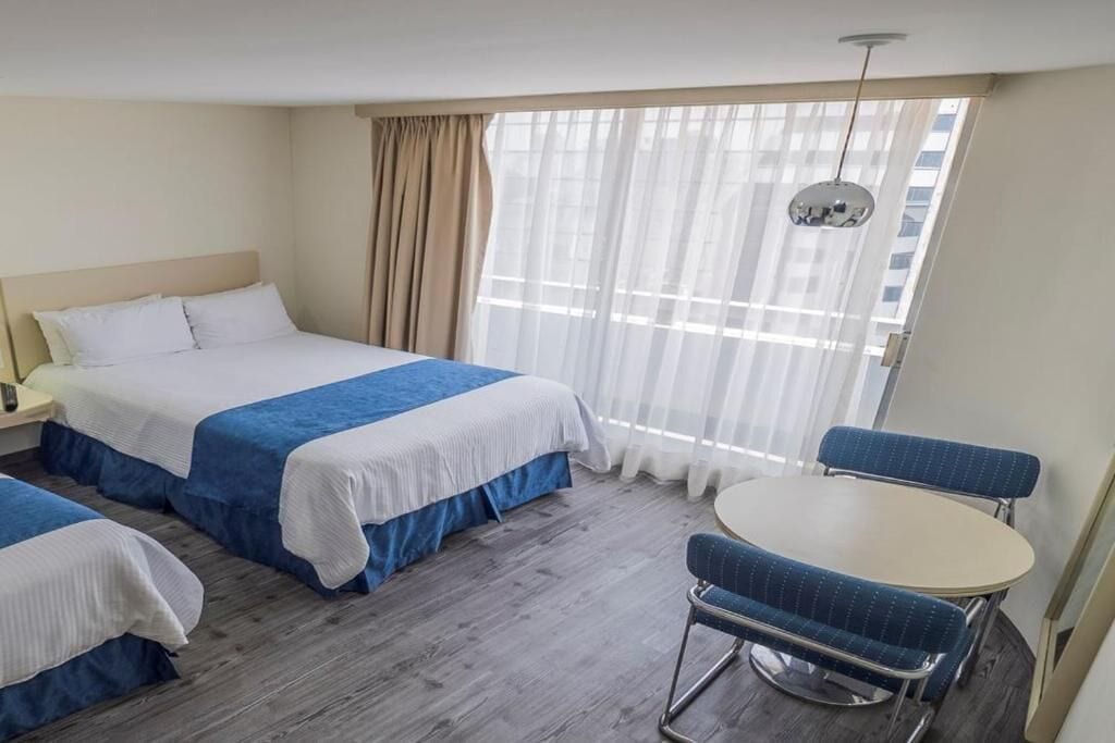 Habitación de hotel con dos camas, una mesa redonda y una silla.