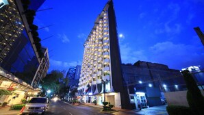 Un hotel moderno con un diseño arquitectónico único, que destaca por una estructura vertical con ventanas iluminadas.