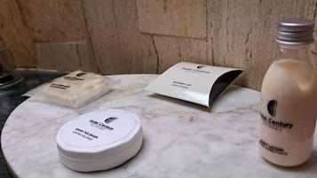 Ein Badezimmer-Waschtisch mit Duschhaube vom Hotel Century, einer Seife und einer Flasche Schuhpolitur.