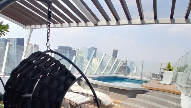 Terraza en la azotea con una silla colgante, piscina y vistas de la ciudad.