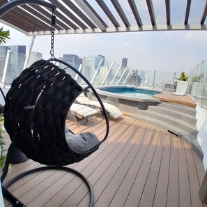 A rooftop terrace with a hanging chair, a pool, and a city view. - Hotel Century Reforma (Mexico City)