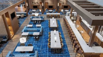 A modern hotel lobby with multiple seating areas, including sofas, tables, and a bar area.