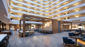 A modern hotel lobby with multiple seating areas, a central bar, and a high ceiling with linear lighting. - Marriott Madison West (Madison)