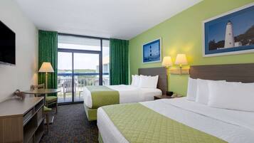 A hotel room with two beds, a desk, and a chair. There is a balcony with a view.