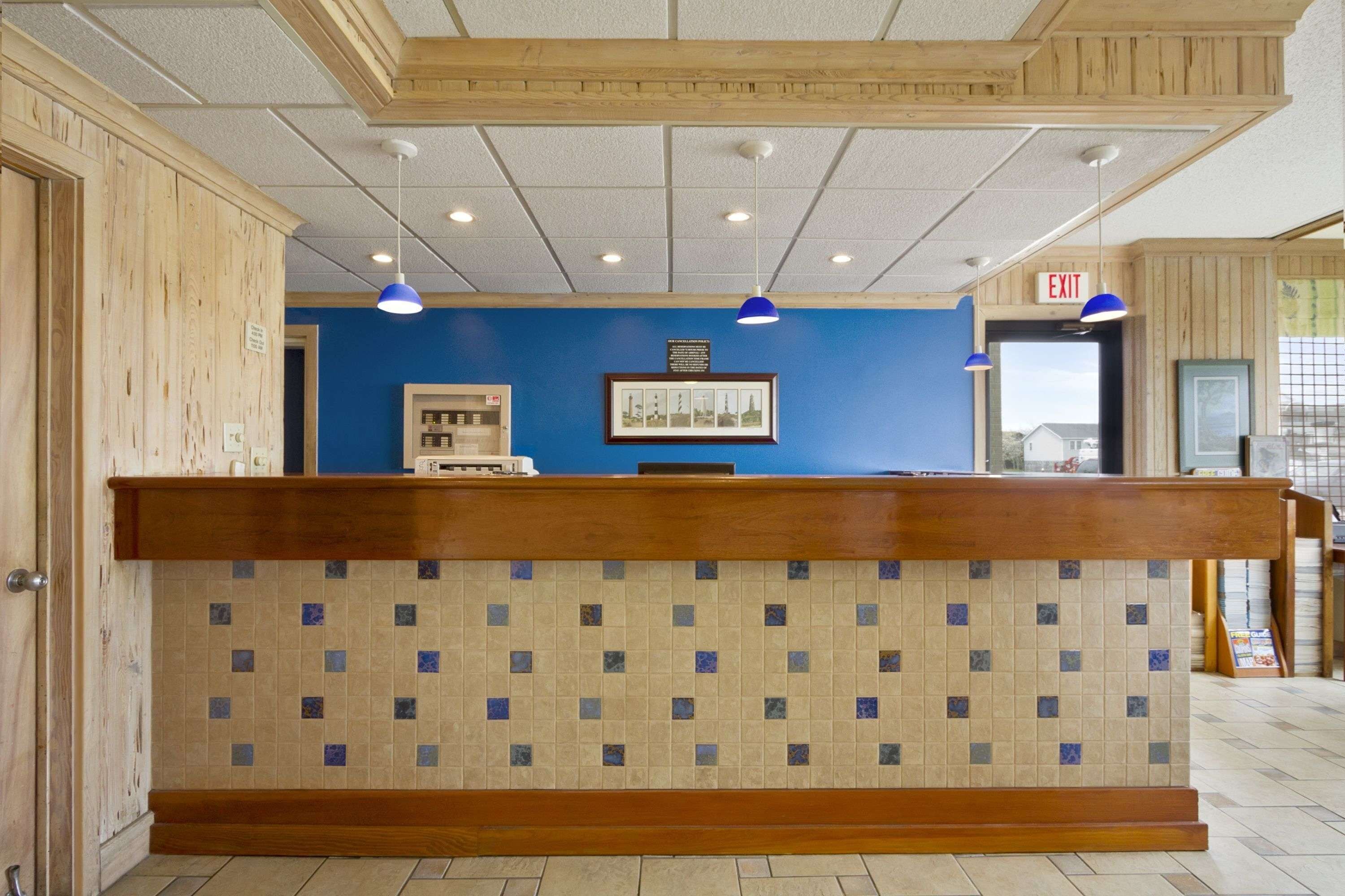Un comptoir d’accueil avec un mur arrière recouvert de carreaux, des lambris en bois sur les murs et un mur bleu derrière le comptoir.