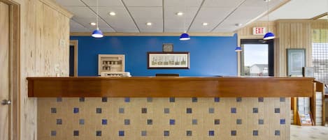 A reception desk with a tiled back wall, wooden paneling on the walls, and a blue wall behind the desk.
